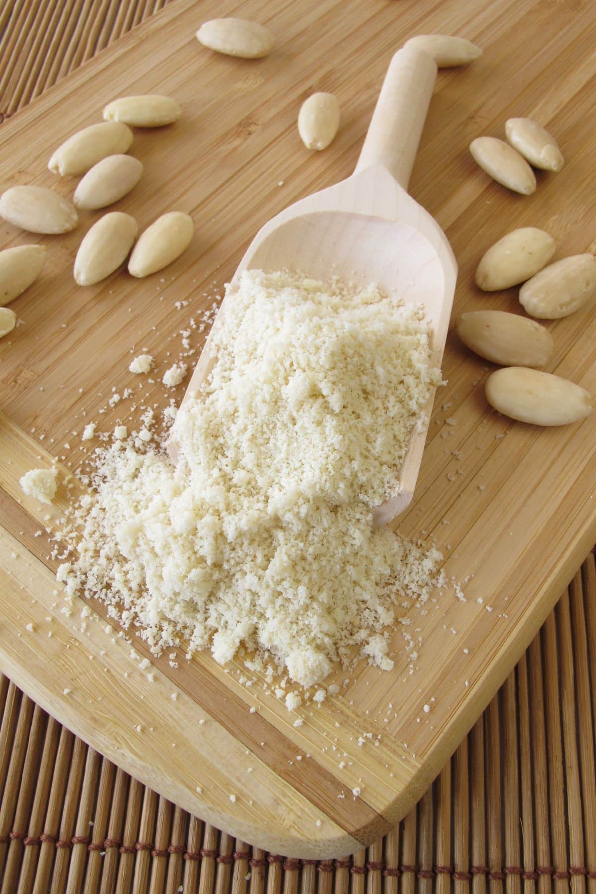 Wooden scoop with almond flour and raw almonds.