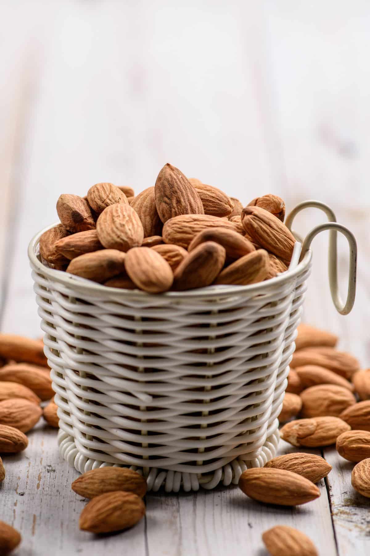 Container of almonds with almonds on table.
