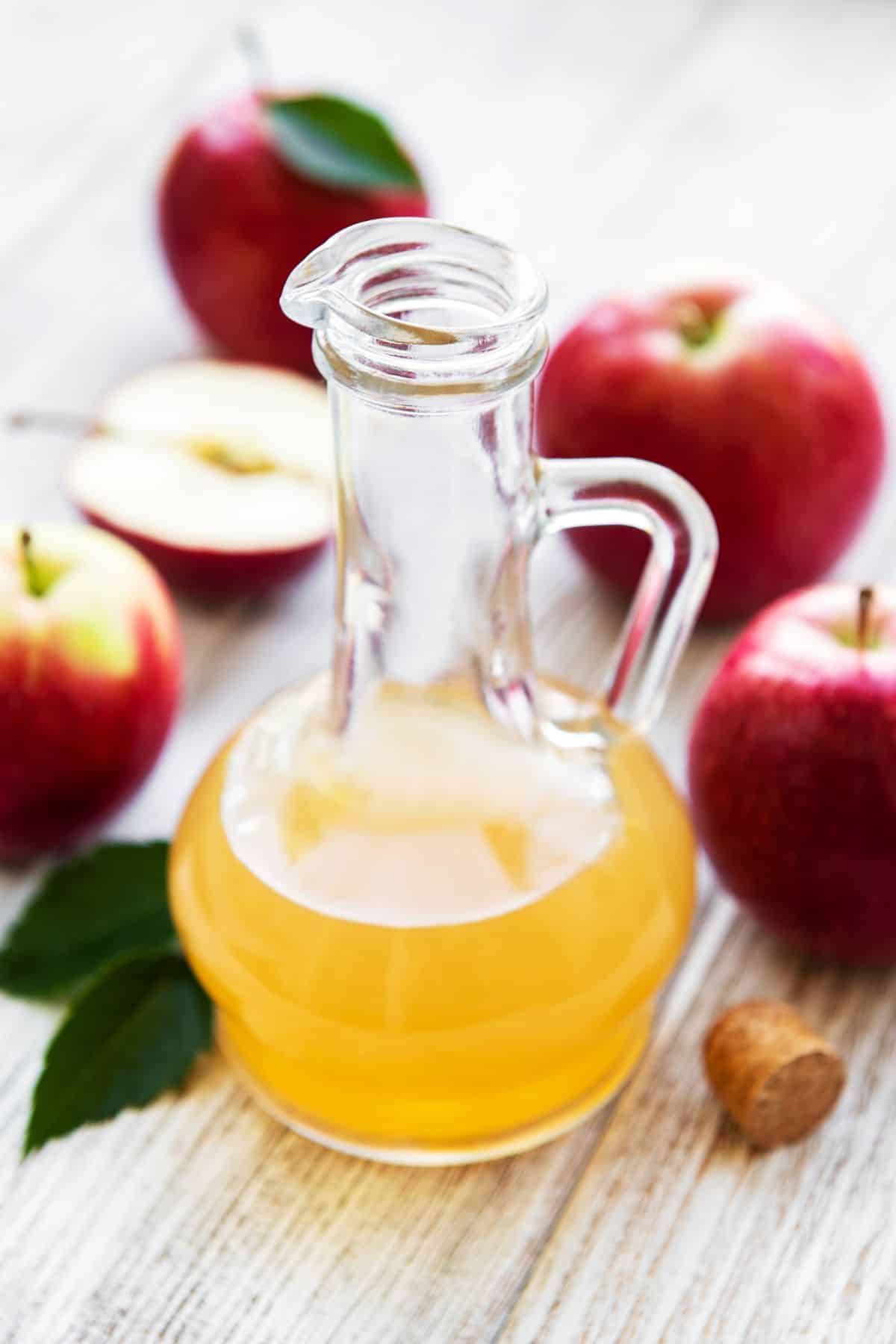 Bottle of apple cider vinegar with apples.