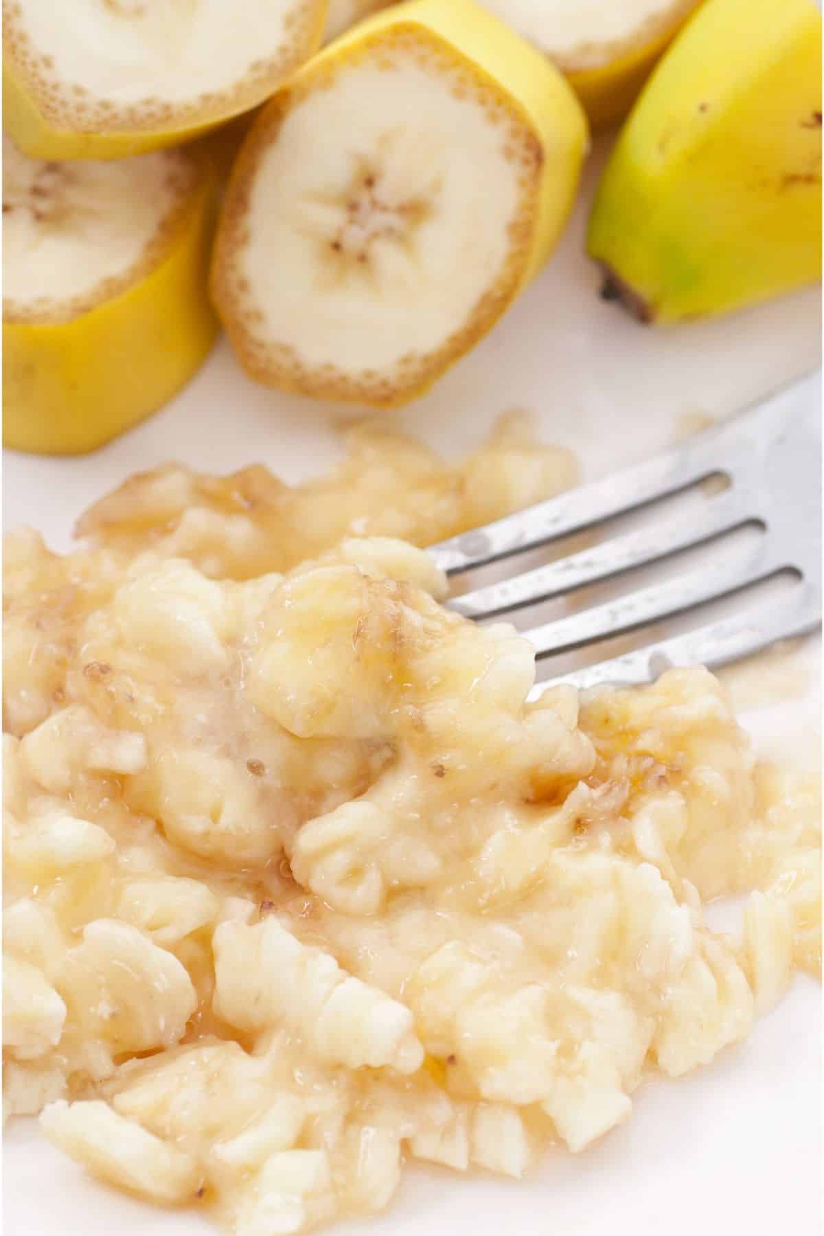 Fork mashed banana beside sliced bananas.