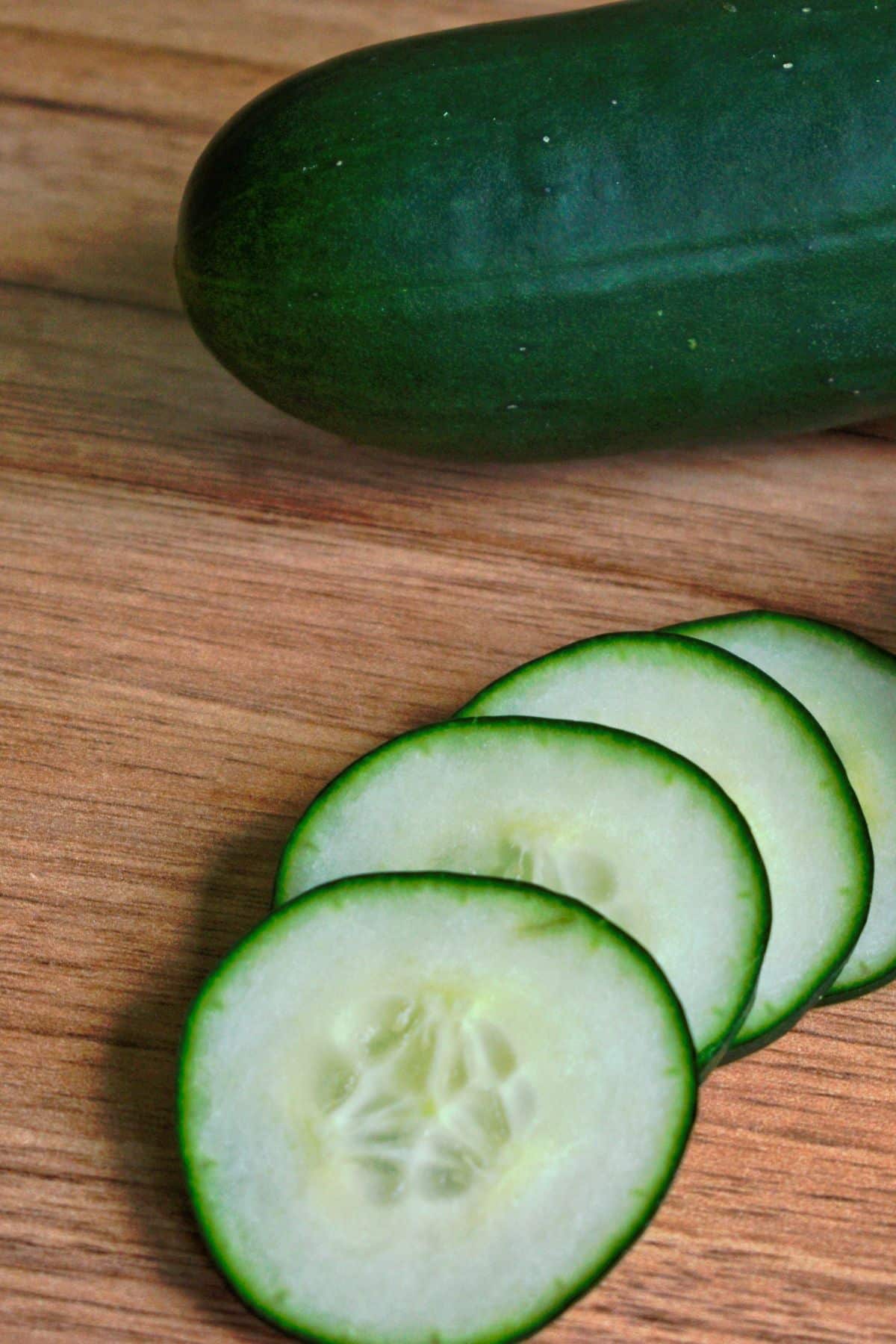 Cucumber slices on a wooden cutting board.