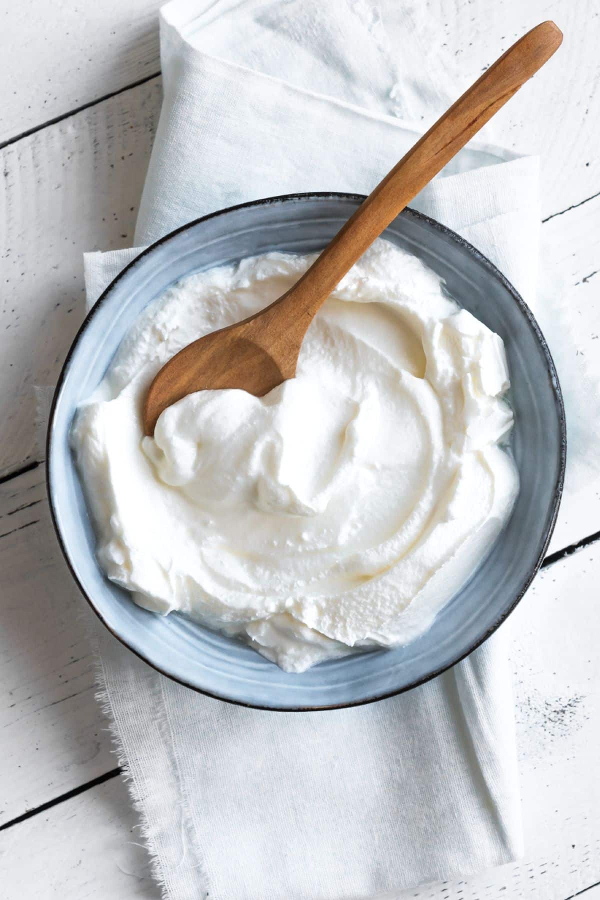 Bowl of greek yogurt with wooden spoon.