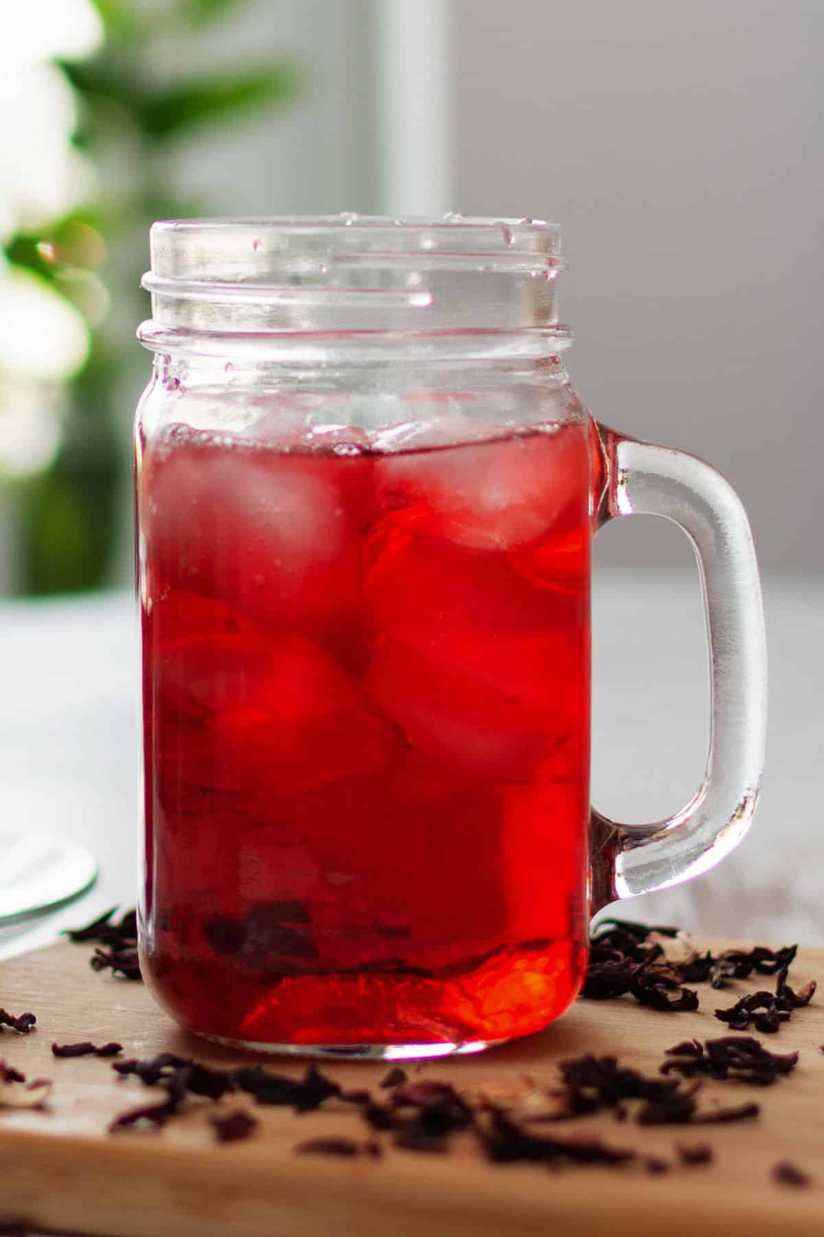 Clear glass mug filled with red hibiscus tea.