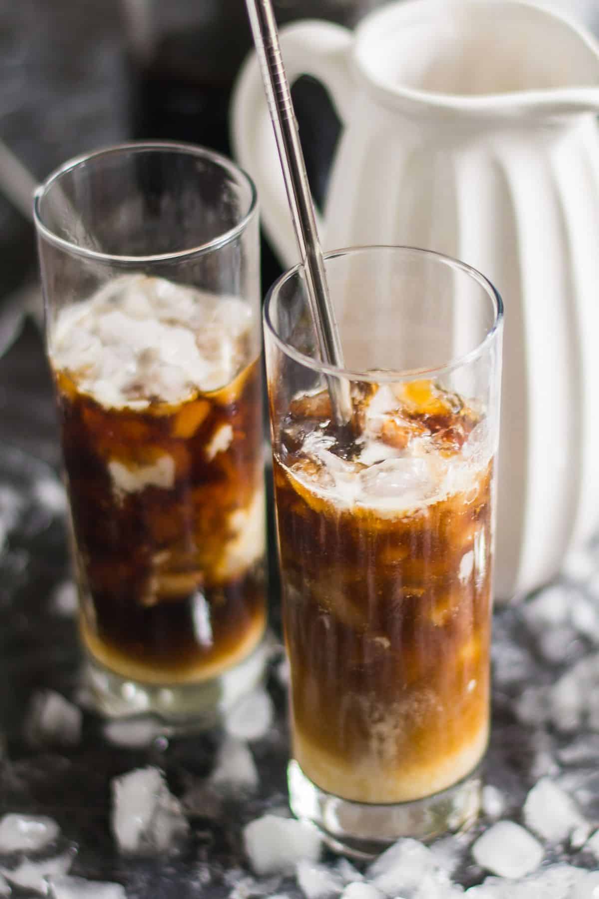 Two glasses filled with coffee and ice.