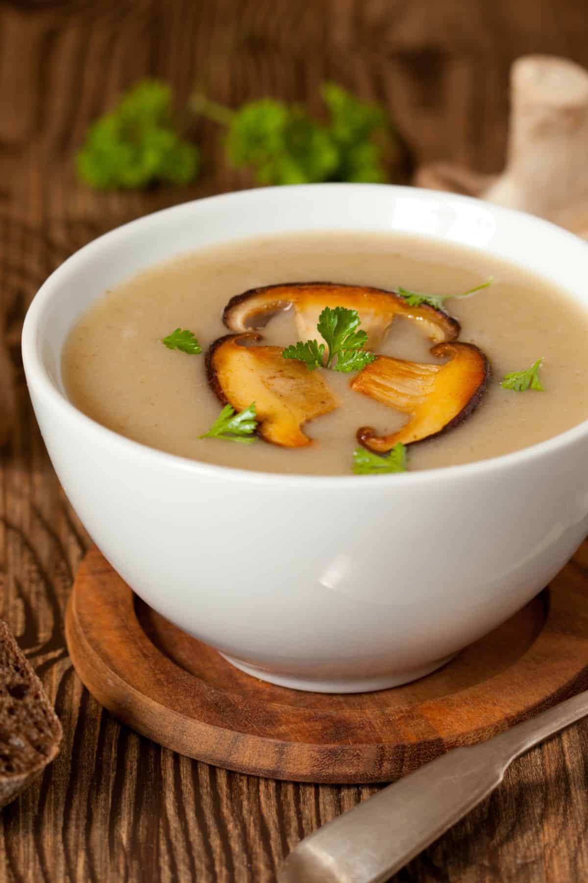 Bowl of mushroom broth with mushrooms and herbs.