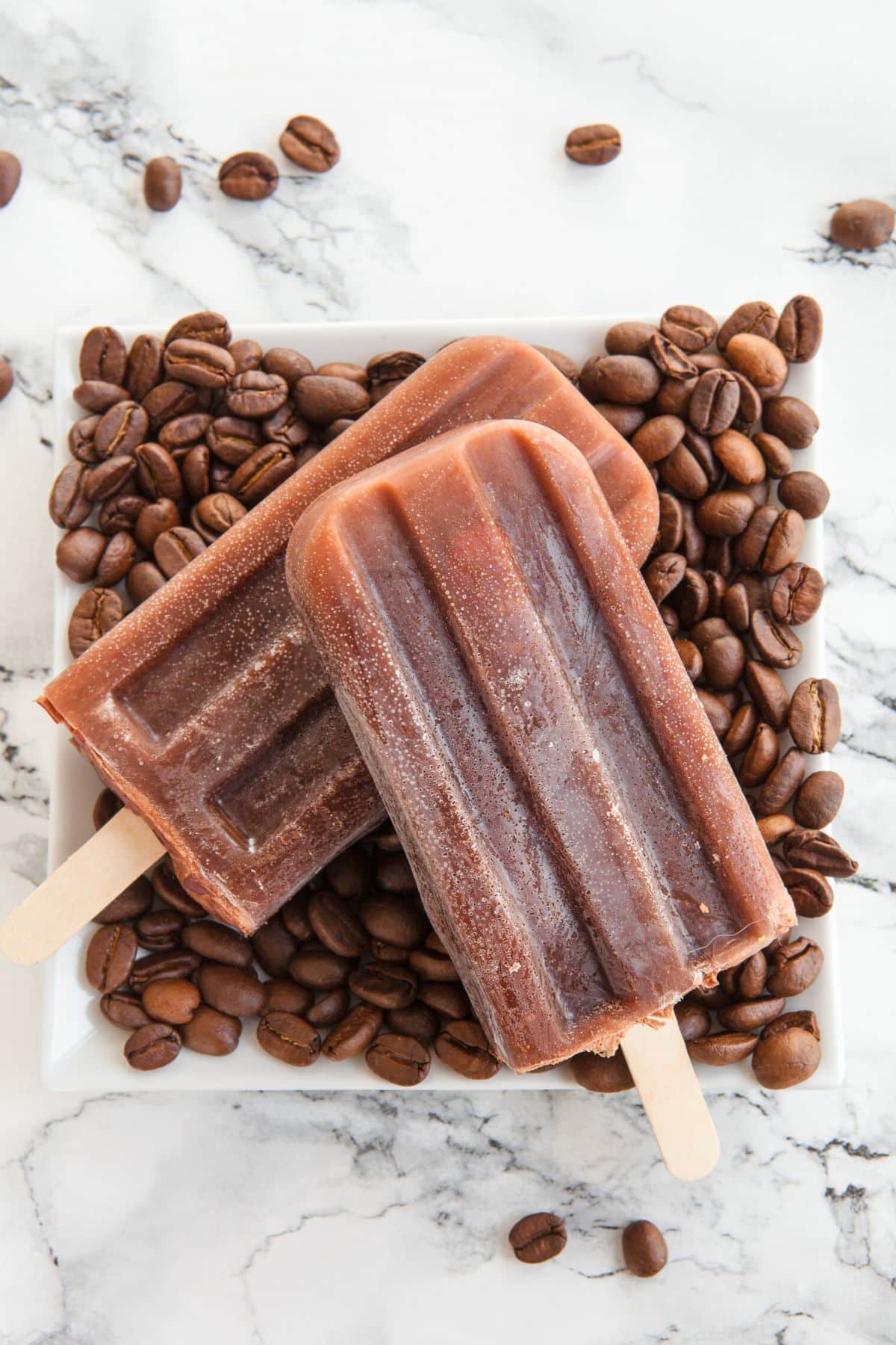 Two coffee popcicles on top of coffee beans.