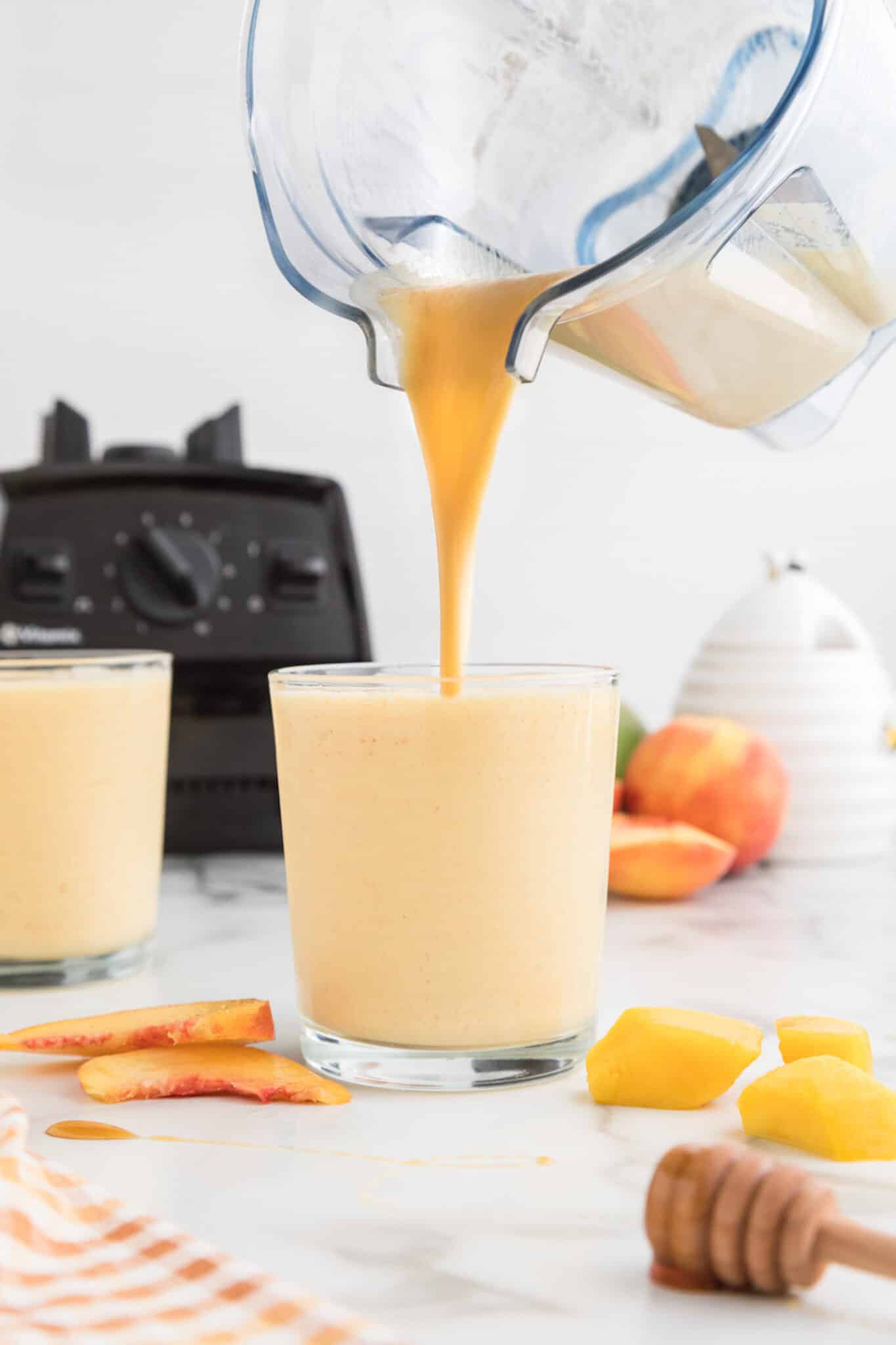 pouring mango peach smoothie from blender into glass.