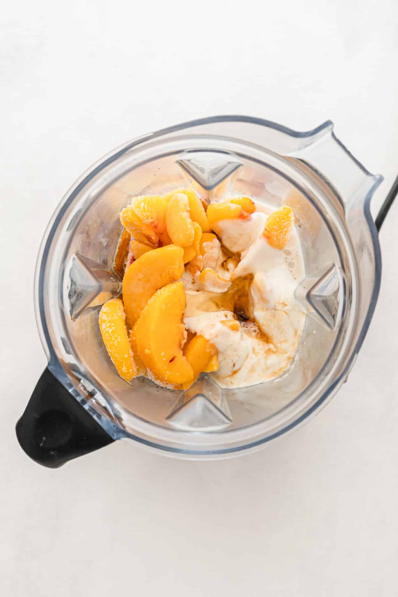 Ingredients for a peach banana smoothie in the jar of a blender.