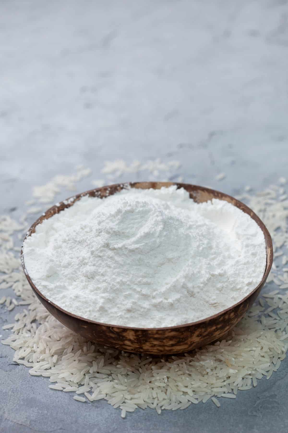 Bowl of rice flour with grains of rice.