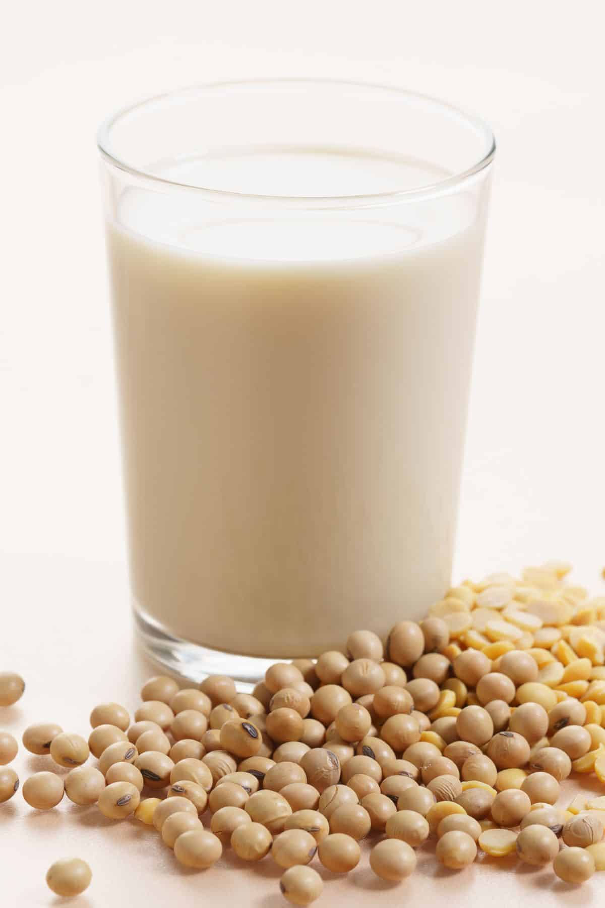Glass of soy milk with dried soy beans on table.