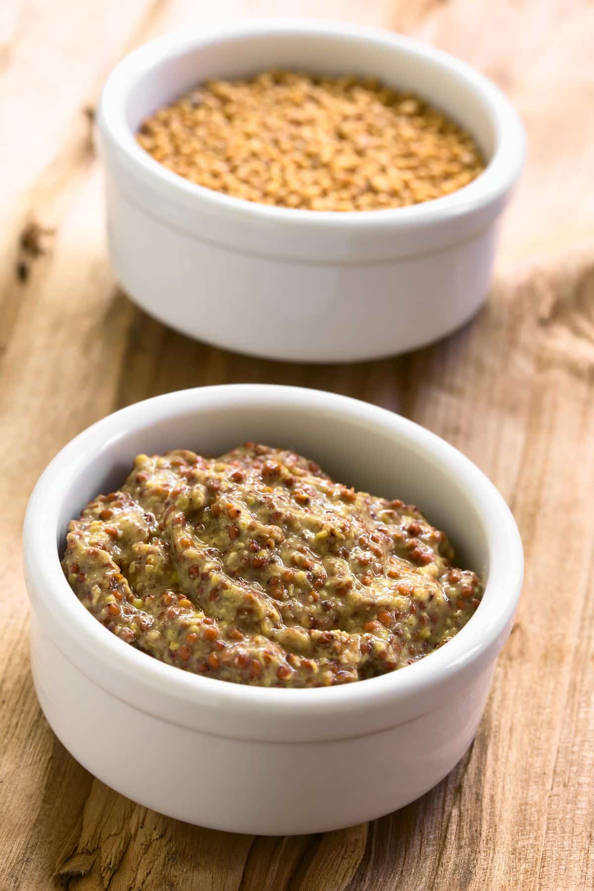 Bowl of spicy brown mustard and mustard seeds.
