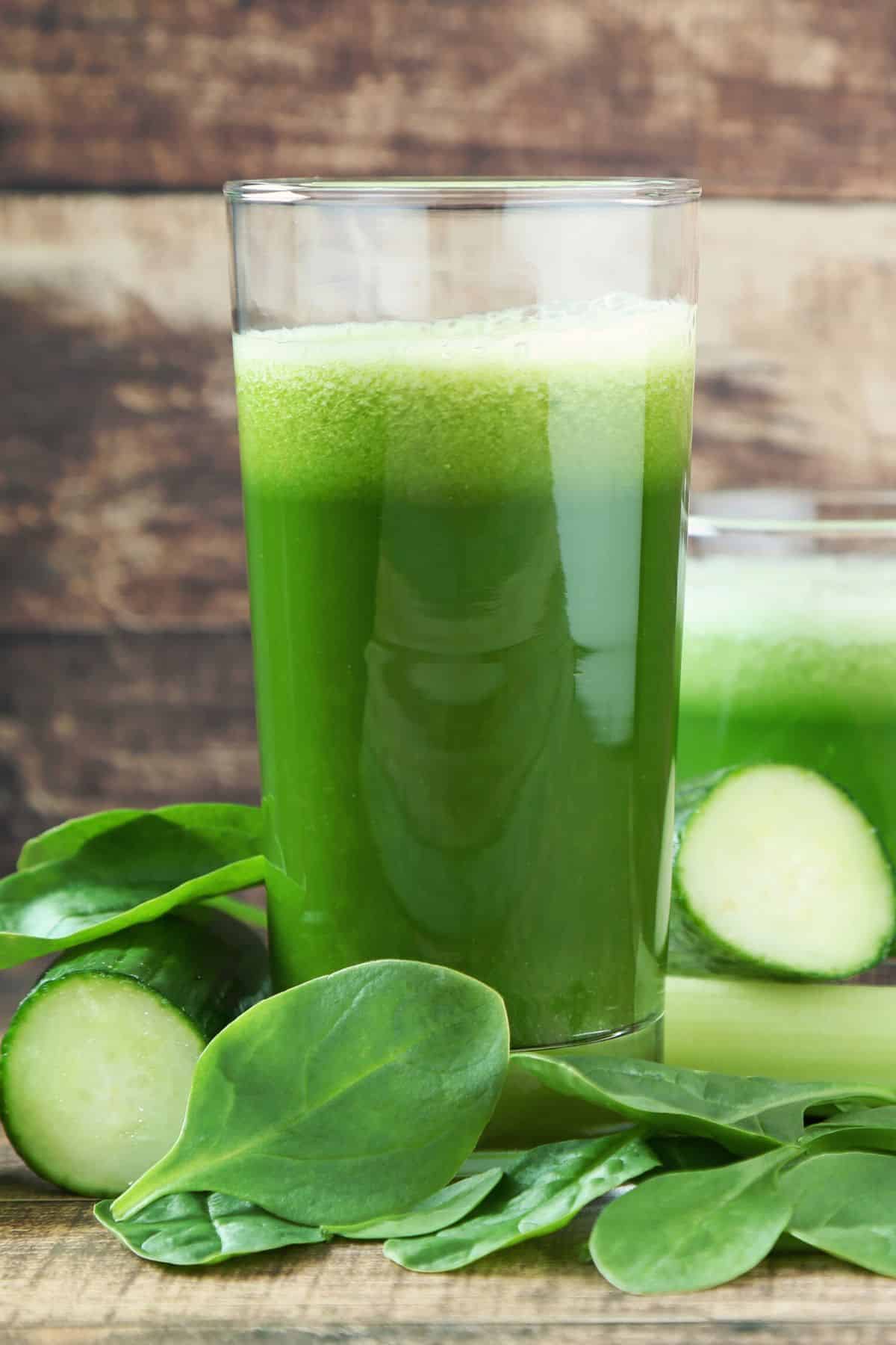 Two glasses of green vegetable juice on a table.
