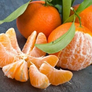 Peeled and unpeeled tangerines on a table.