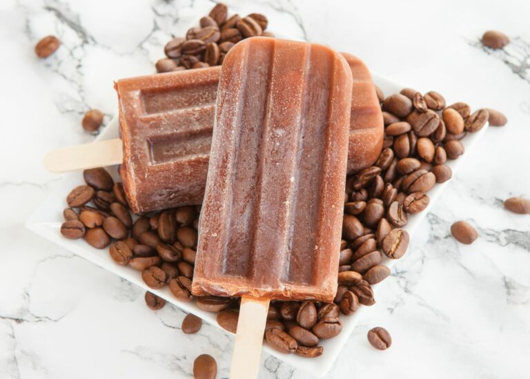 Two coffee popsicles on top of coffee beans.