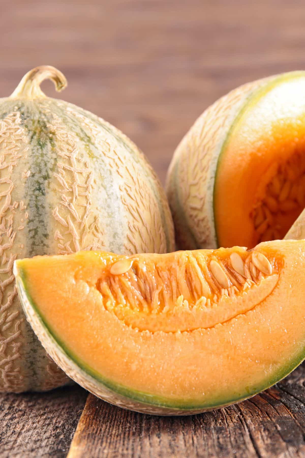 A couple of zebra melons on a wooden surface.