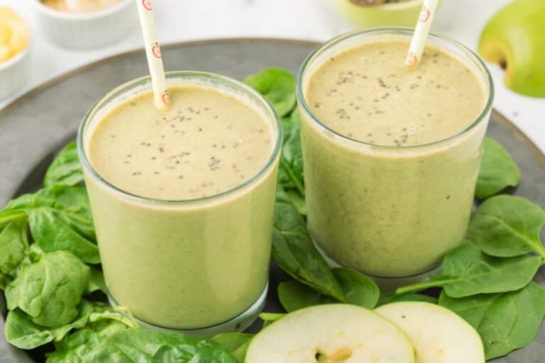 Two short glasses of apple banana smoothie with chia seeds.