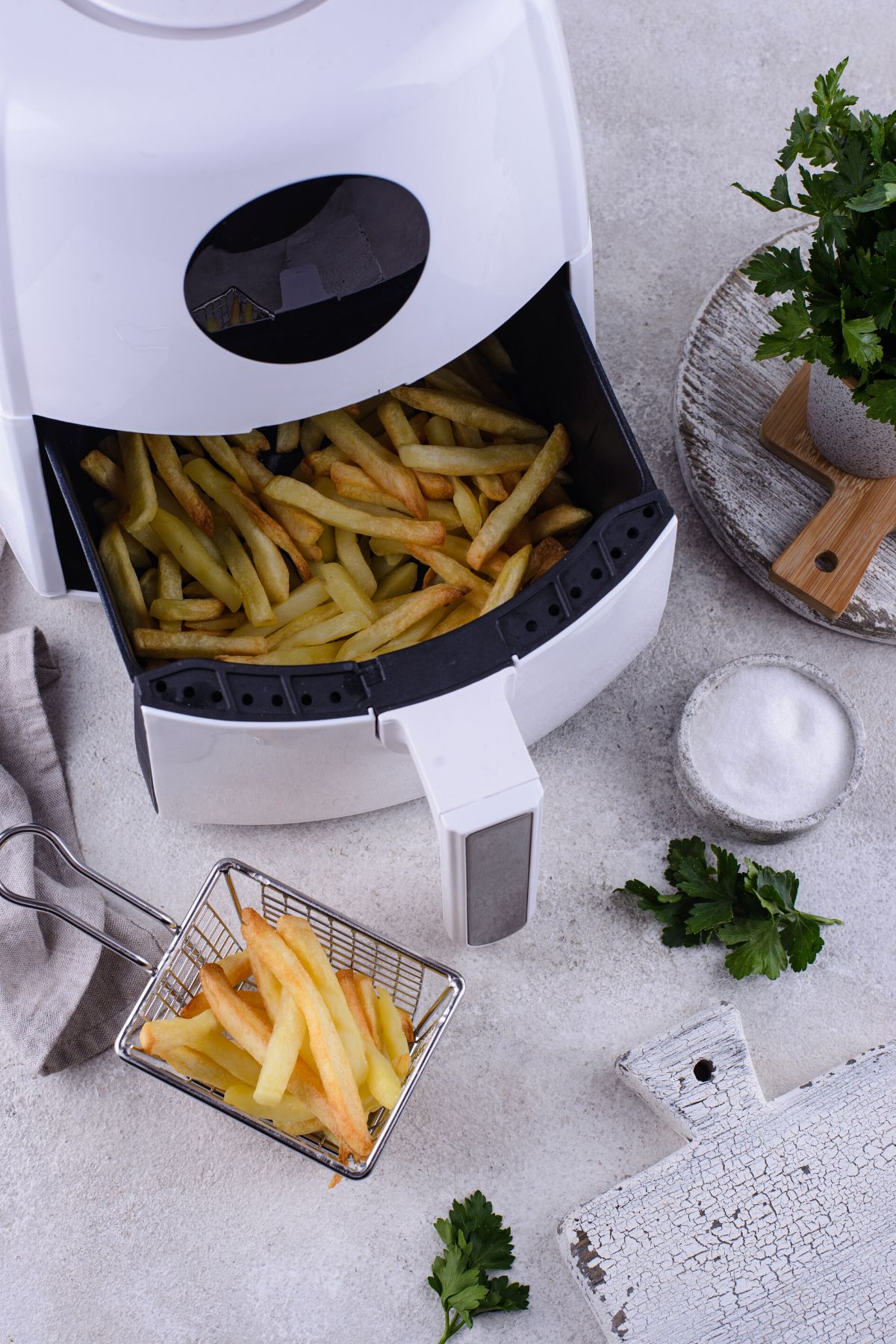 White air fryer open and the basket is filled with fries.