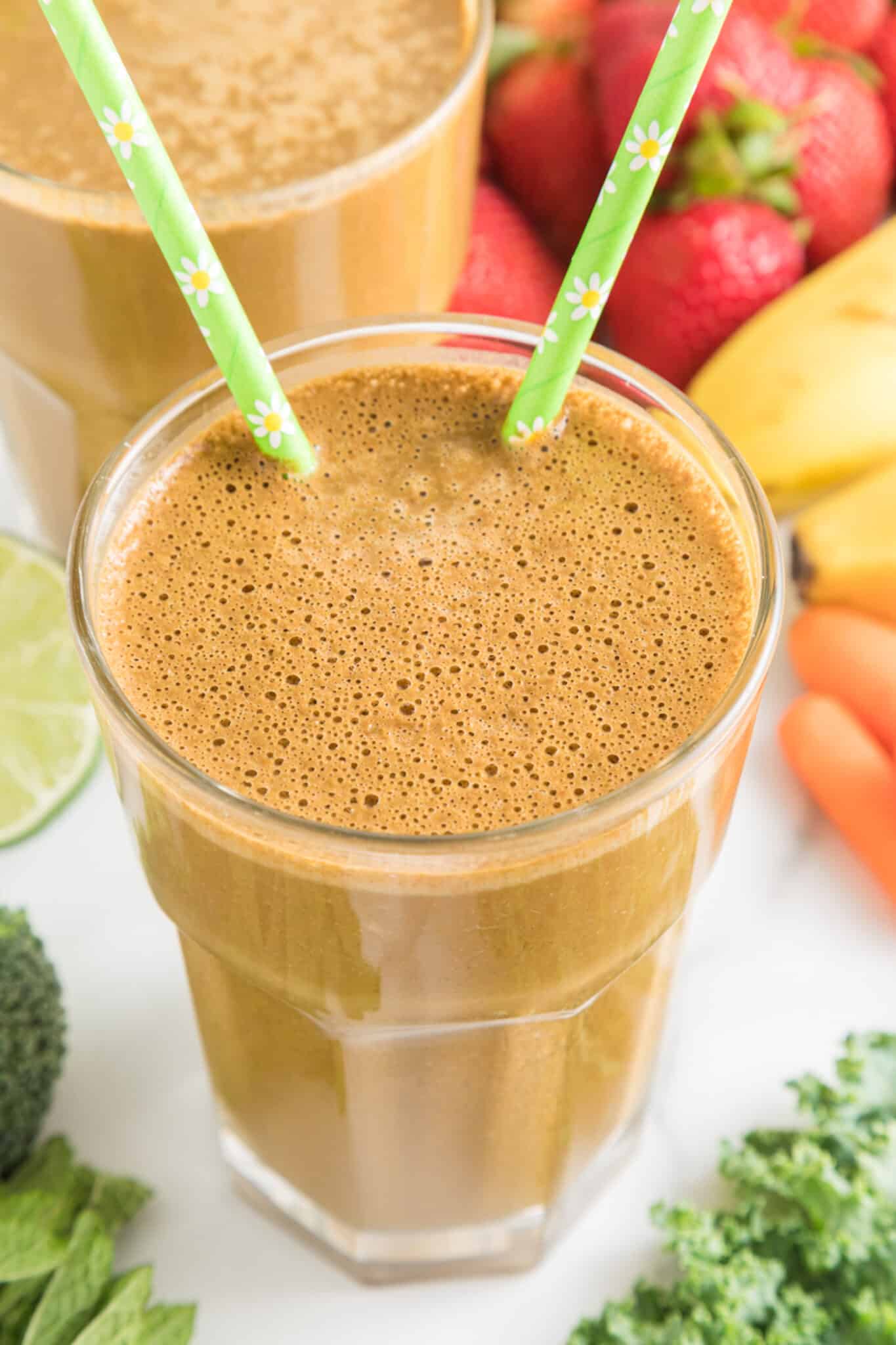 Cocoa green smoothie in a glass with two green straws.