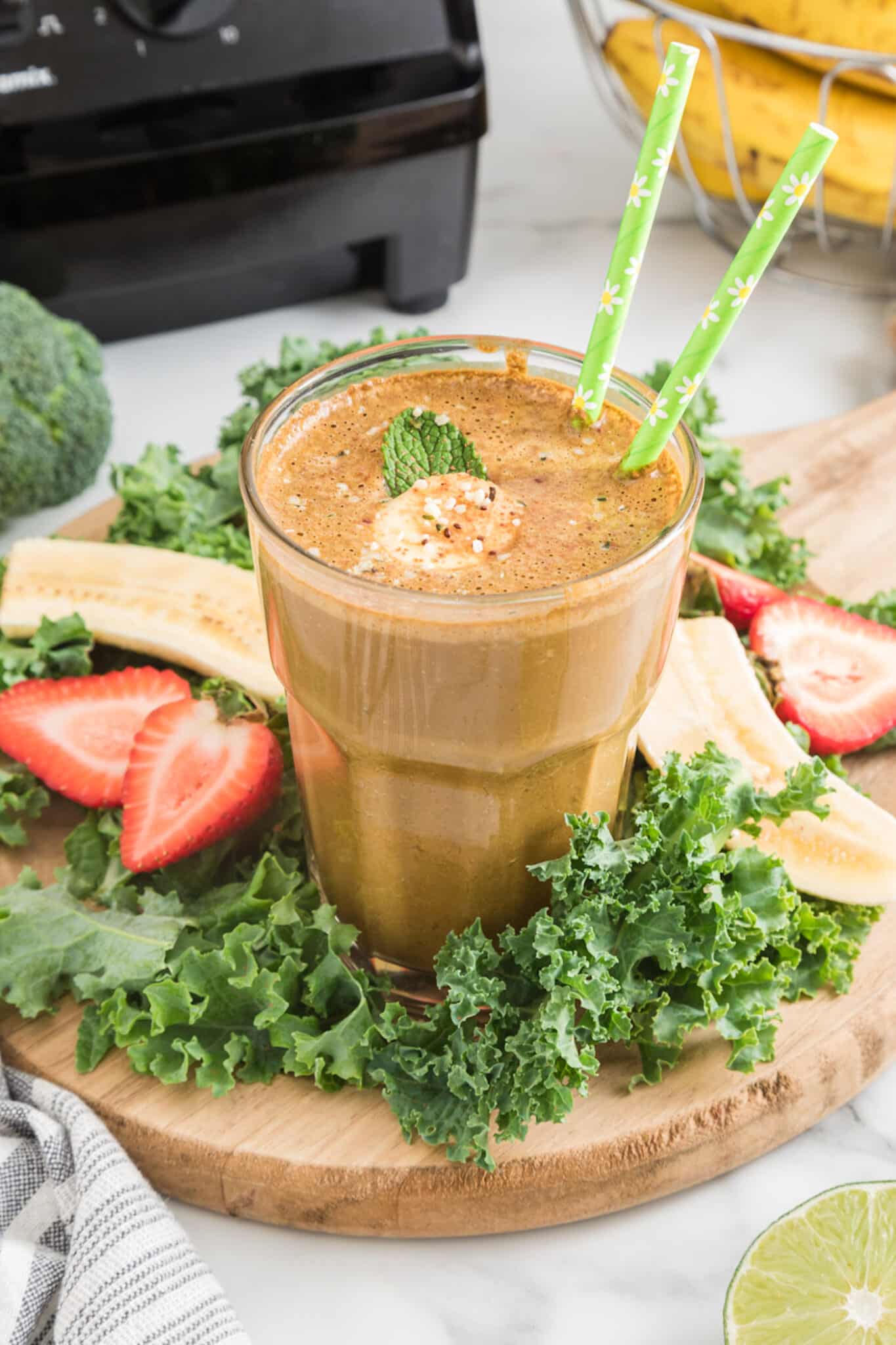 Cocoa green smoothie in a glass with two green straws.