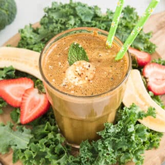 Cocoa green smoothie in a glass with two green straws.