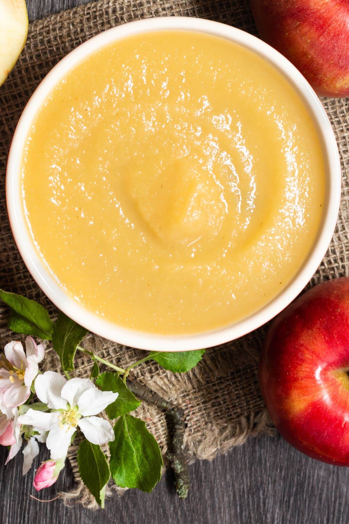 Bowl of applesauce with apples and apple blossoms.