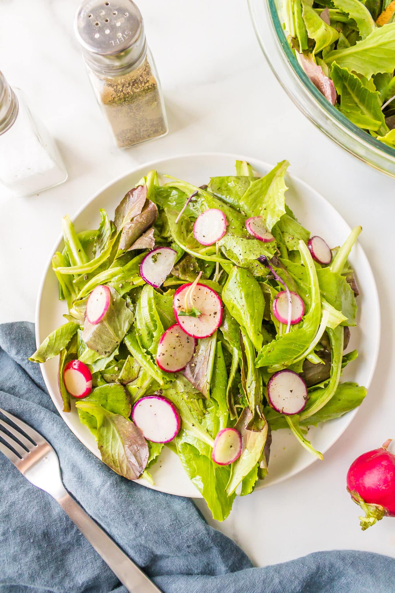 Baby romaine salad with radishes on a white serving platter.