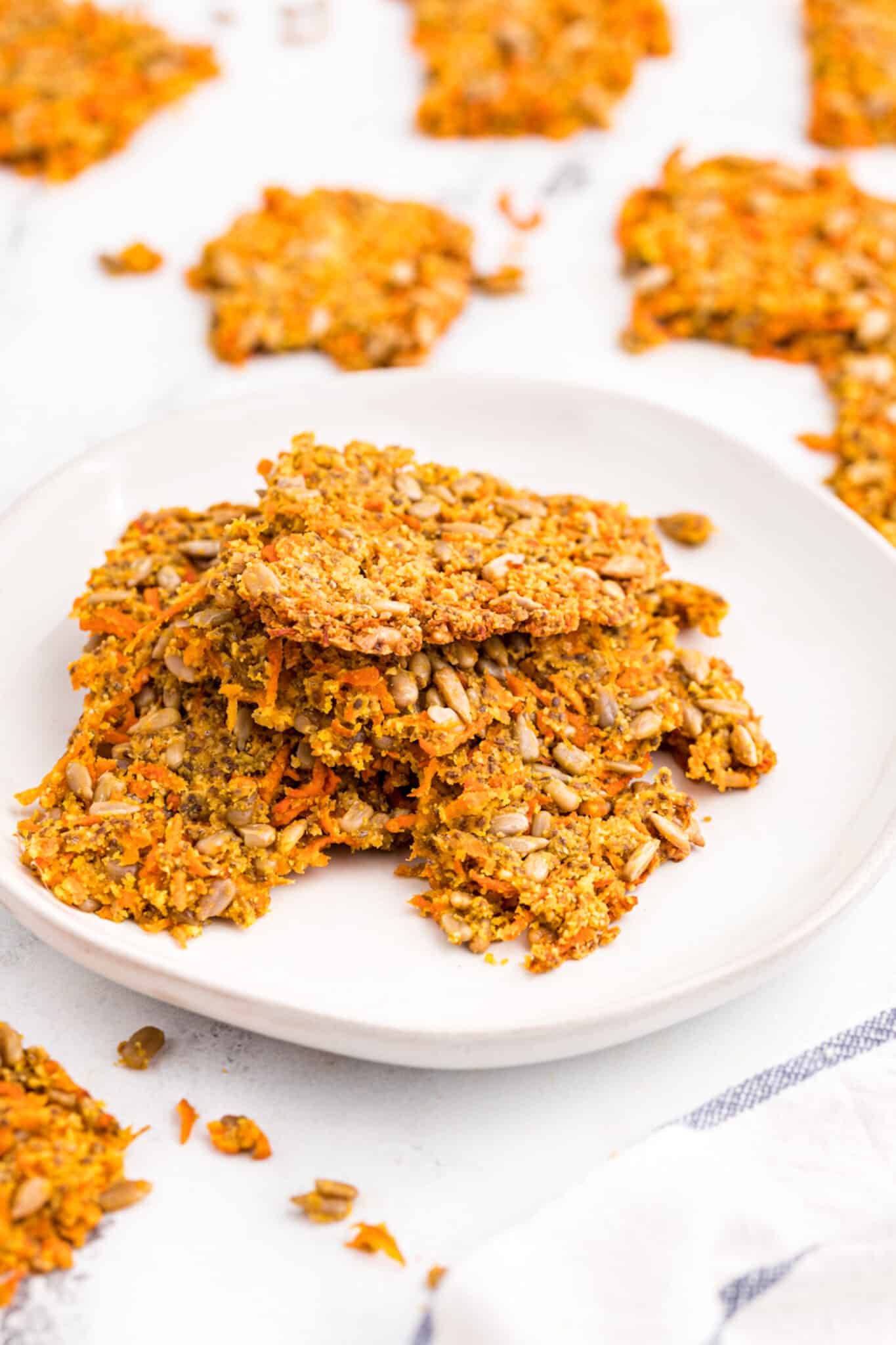 Carrot crackers on a white plate on a tabletop.