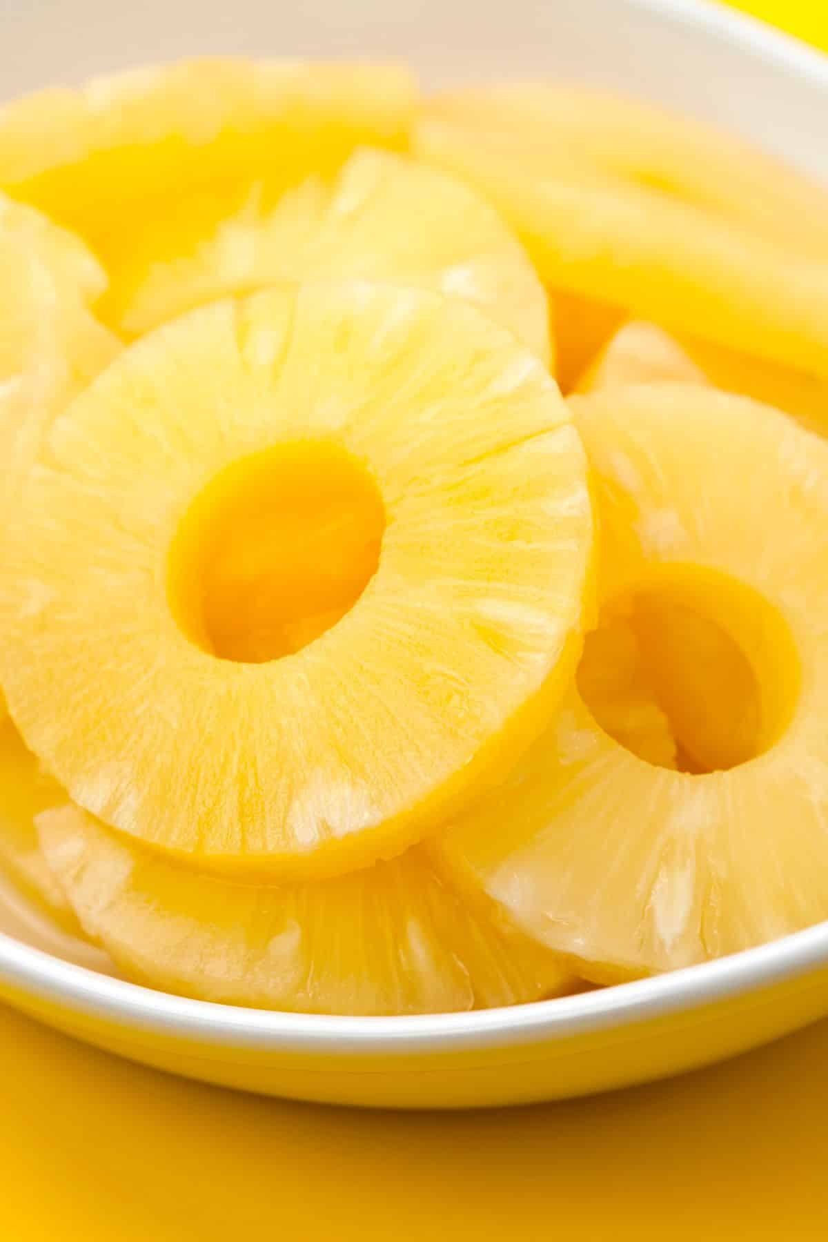 Canned pineapple rings in a white bowl.