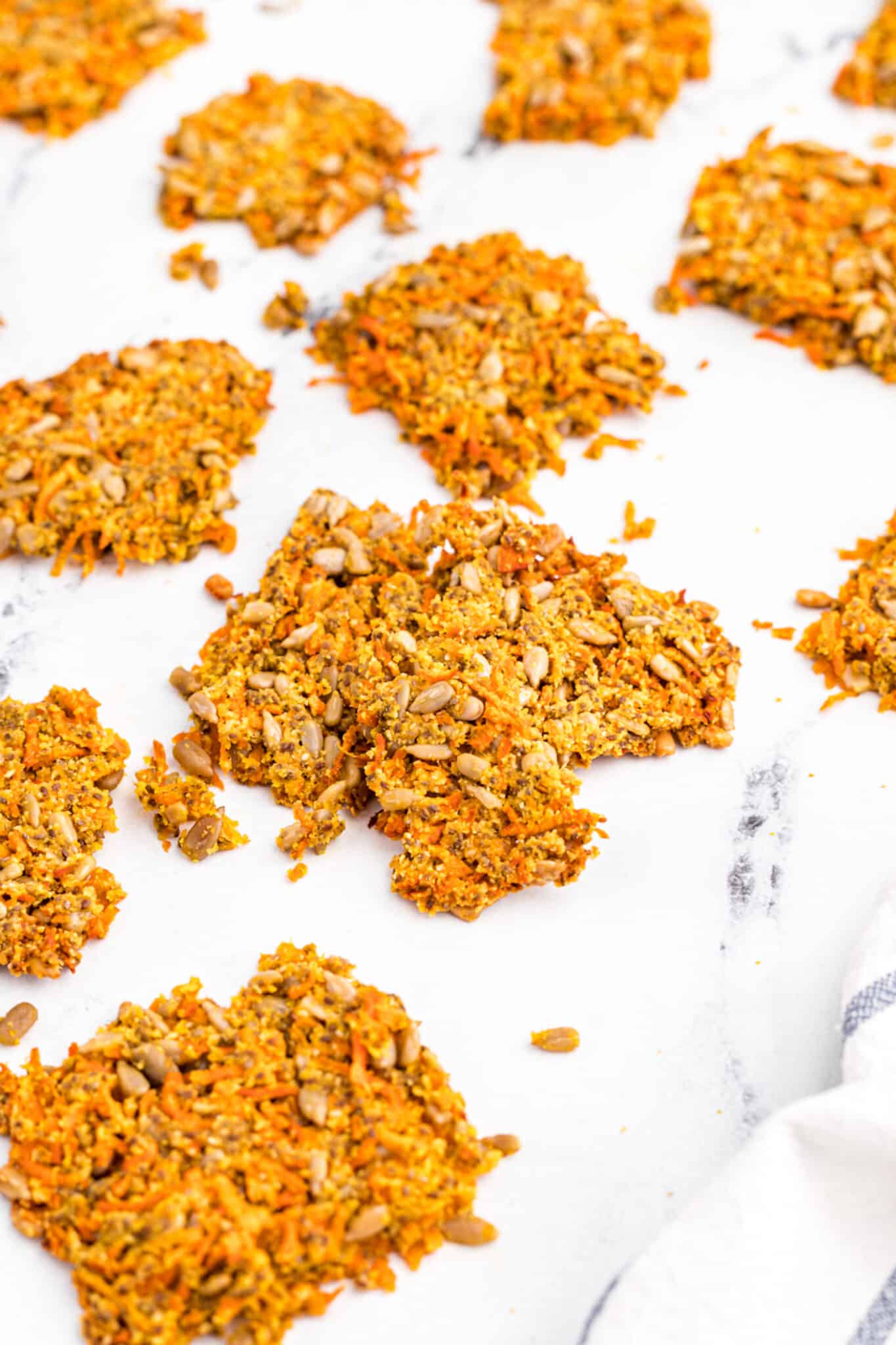 Baked carrot pulp crackers on a white surface.