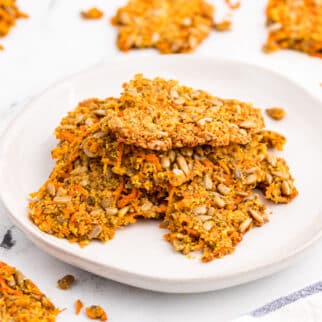 Shredded carrot crackers stacked on a white plate.
