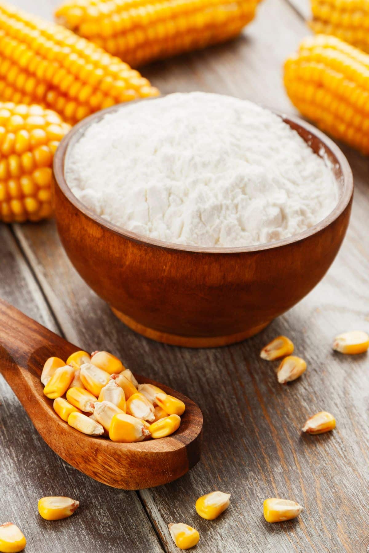 Spoonful of corn kernels with bowl of cornstarch.