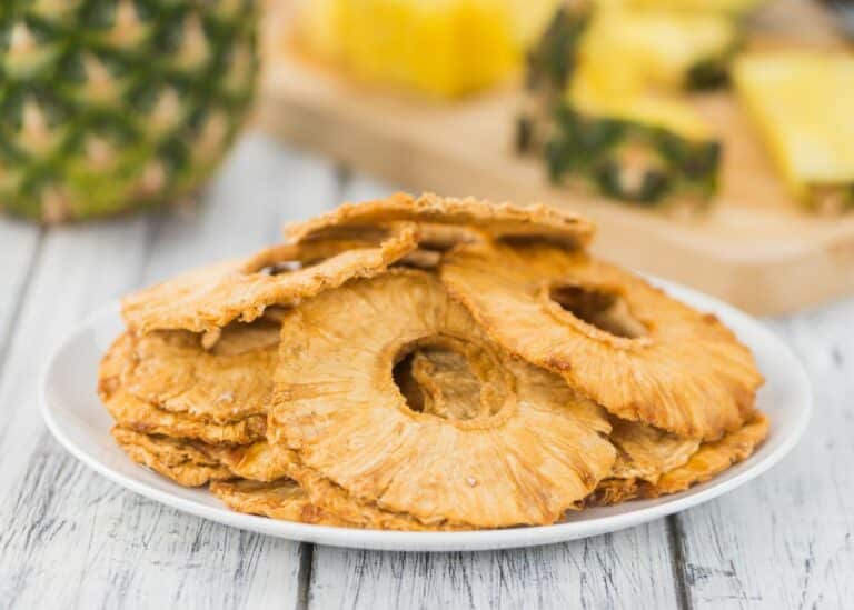 A pile of dehydrated pineapple slices on a white plate.