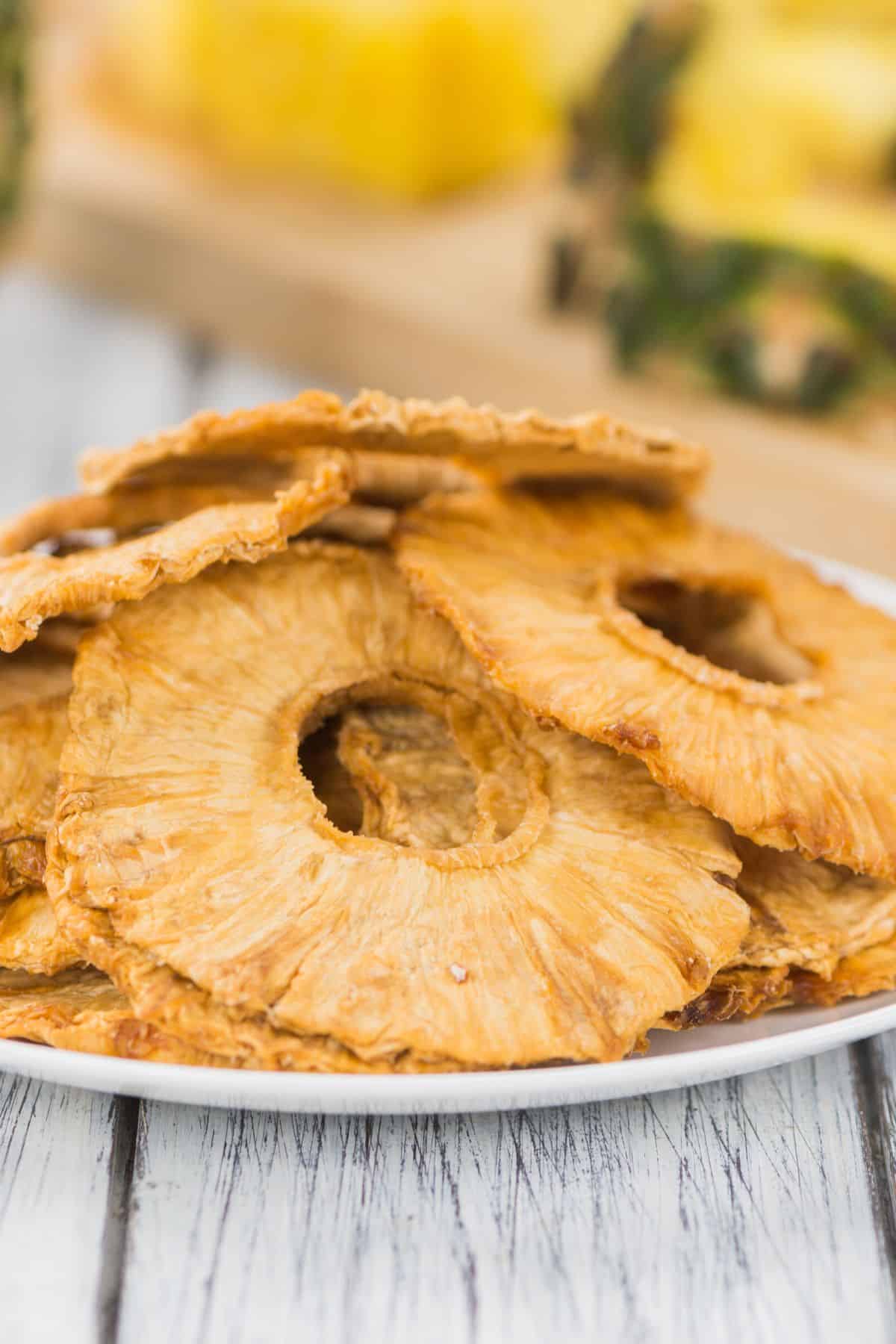 A pile of dehydrated pineapple slices on a white plate.