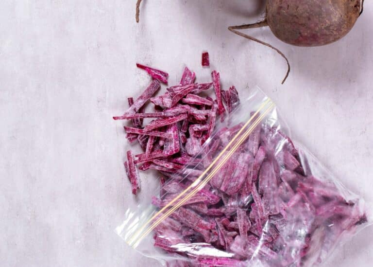 A baggie of frozen shredded beets next to two whole beets.
