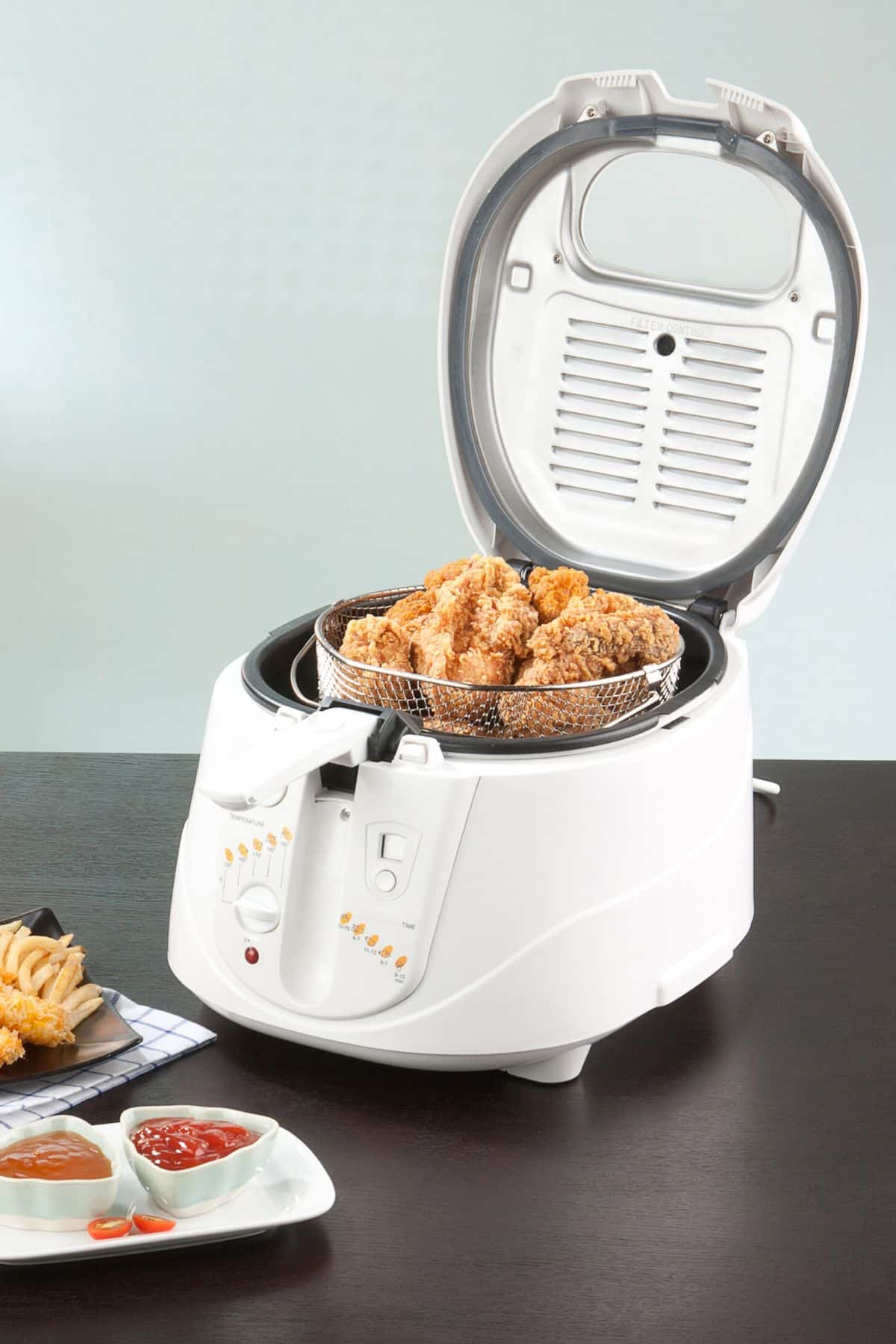 White deep fryer with open lid and fried chicken inside.