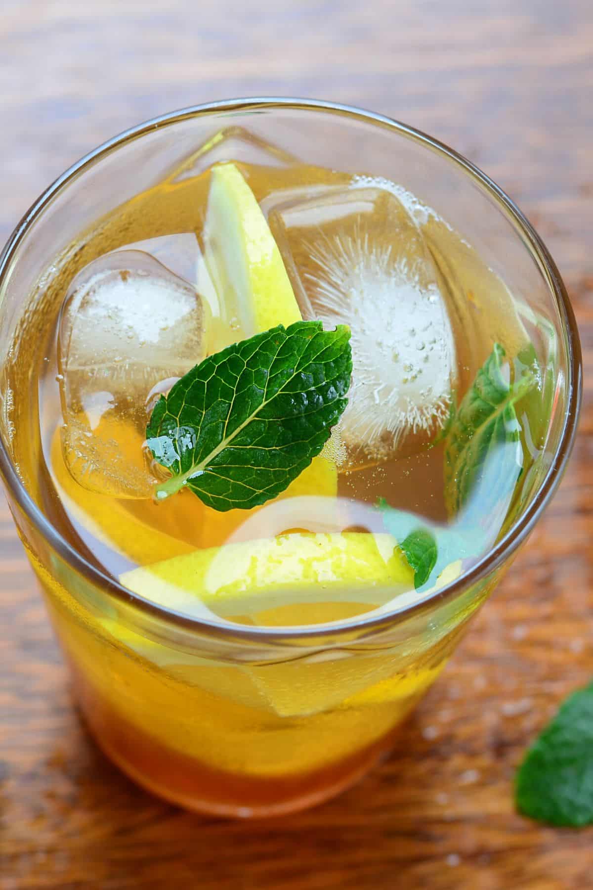 Glass filled with tea, ice, lemon and mint.