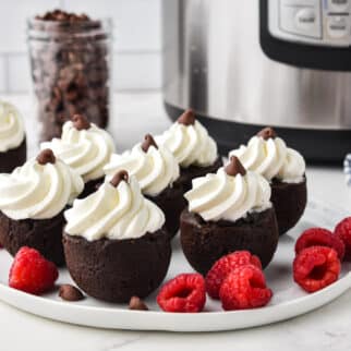Instant Pot brownie bites topping with whipped cream on a white plate.