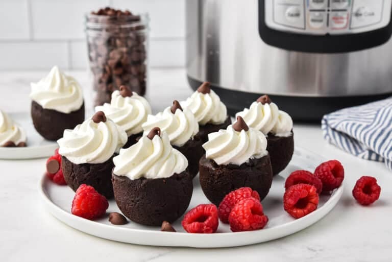 Instant Pot brownie bites topping with whipped cream on a white plate.