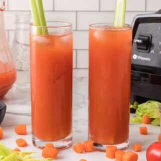 Two tall glasses of tomato juice, each with a stalk of celery.