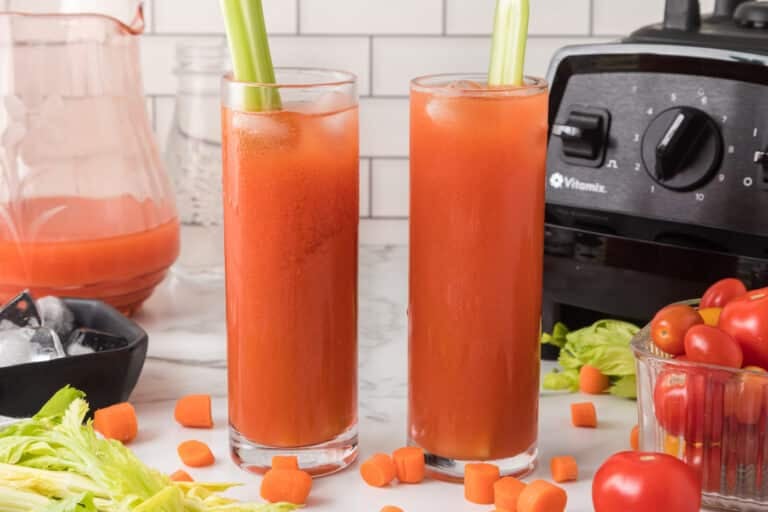 Two tall glasses of tomato juice, each with a stalk of celery.