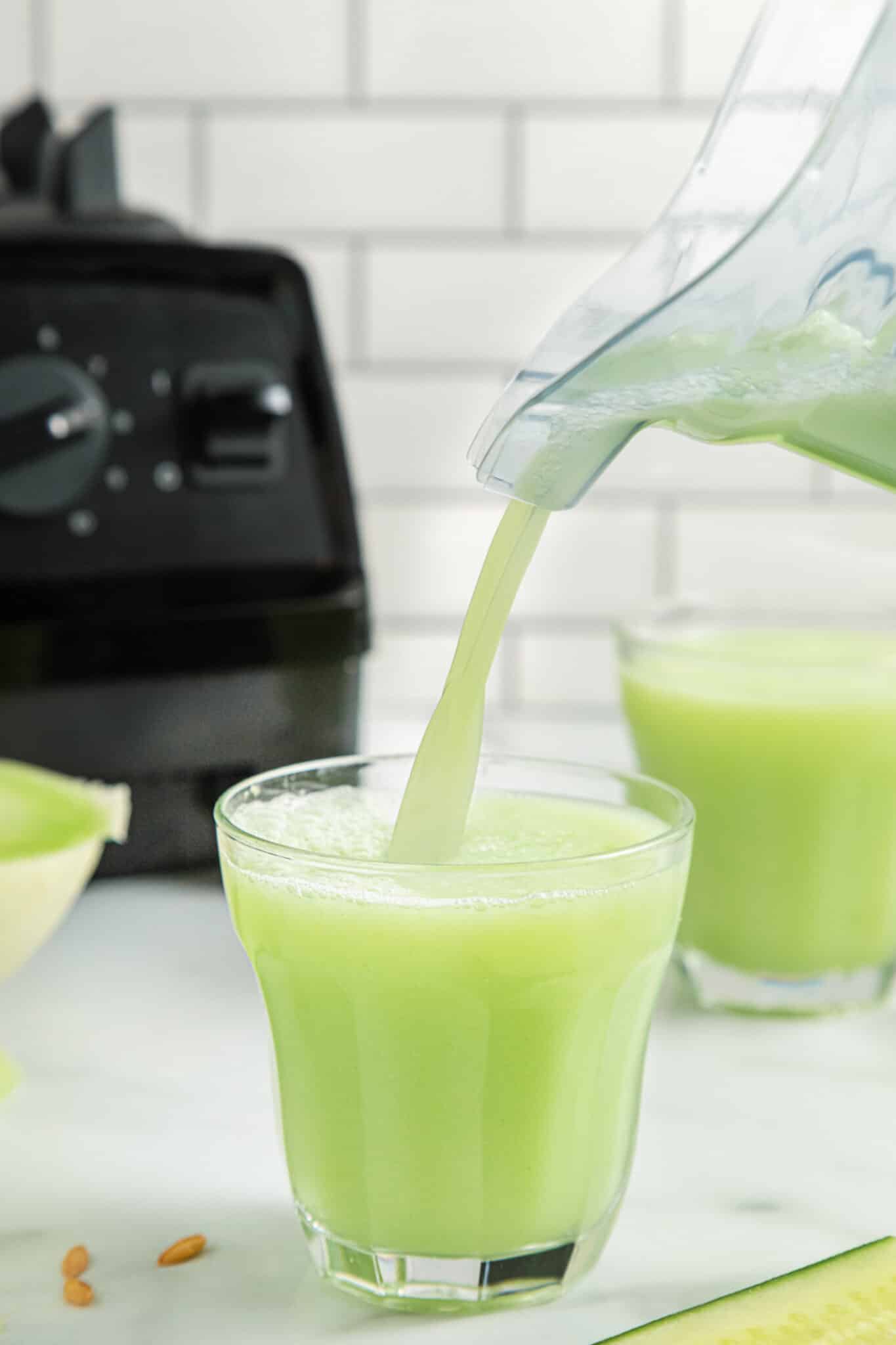pouring honeydew smoothie into glass.
