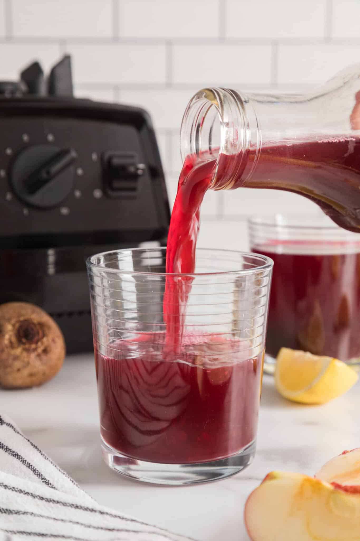 Pouring beet liver cleanse juice into a short glass.