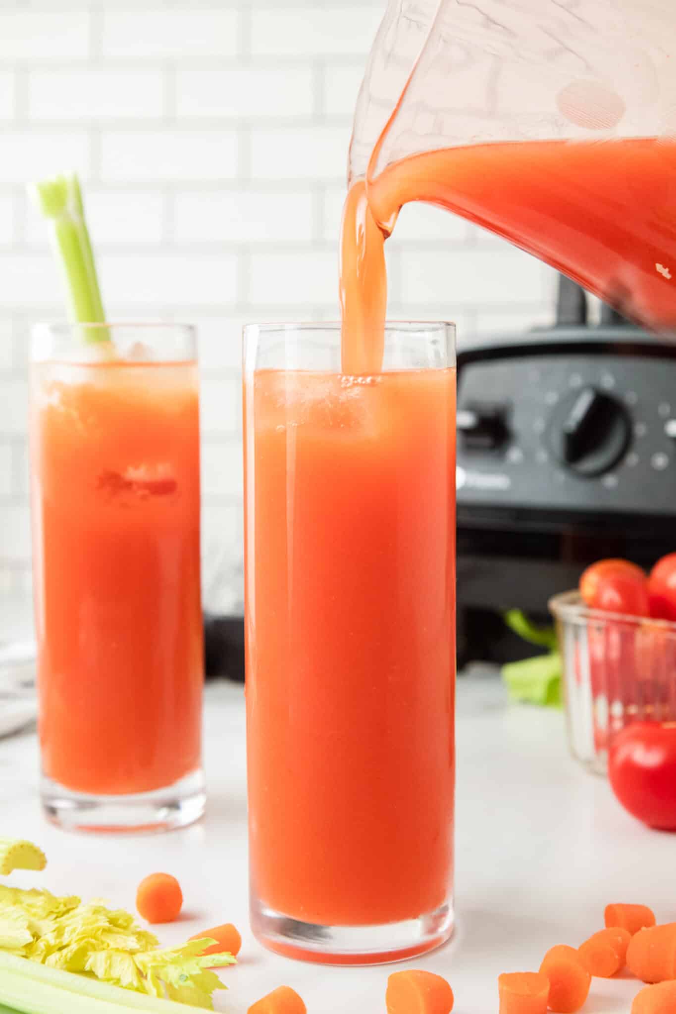 pouring two glasses of tomato juice.
