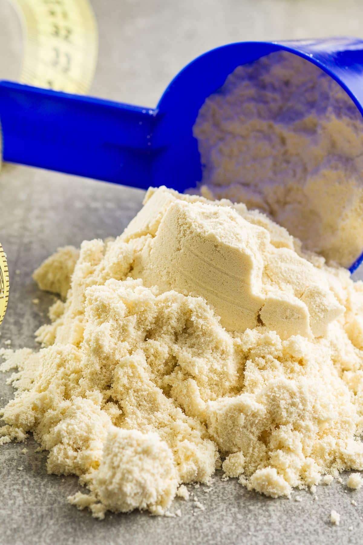 blue scoop with protein powder on a tabletop.