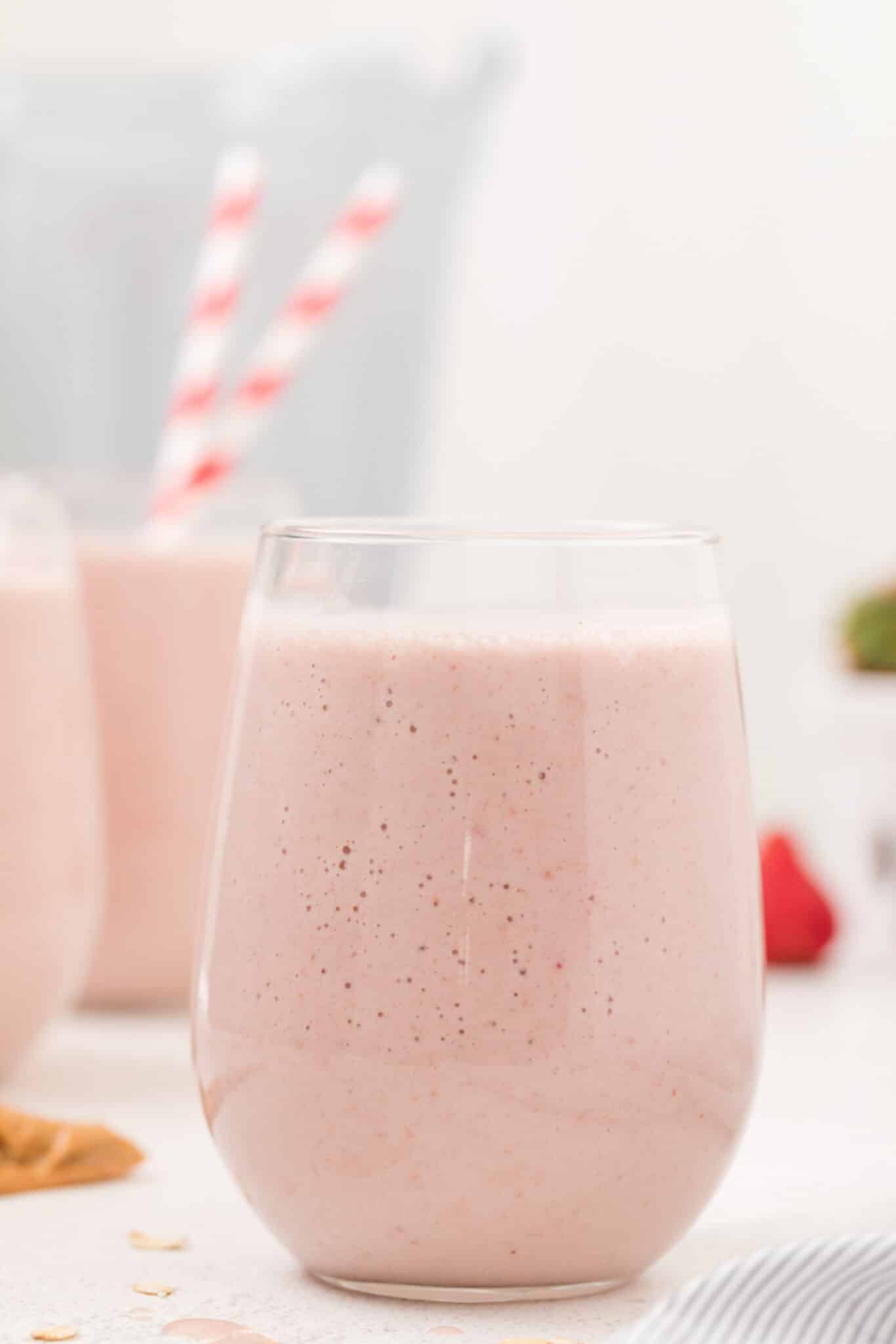 strawberry protein smoothie in a glass on a tabletop.