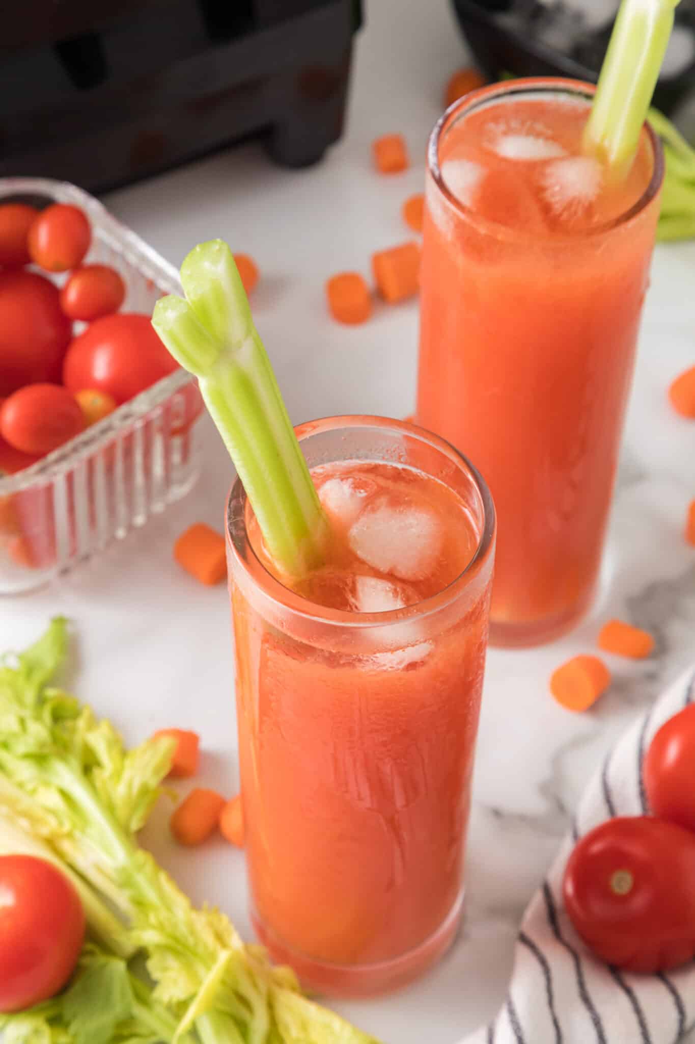 tomato juice recipe served with a stalk of celery and ice cubes.