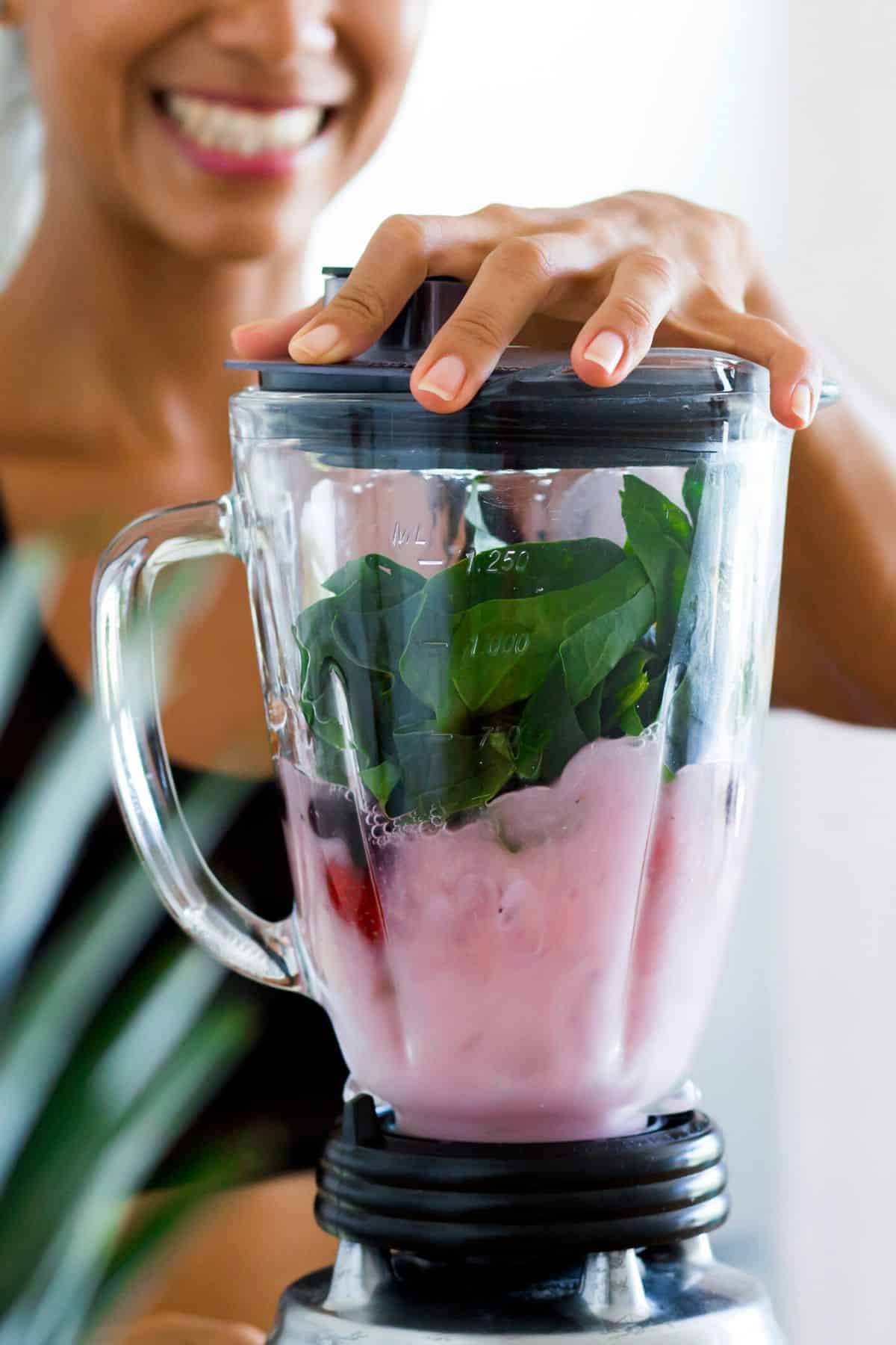 young woman making a green smoothie with fruit.