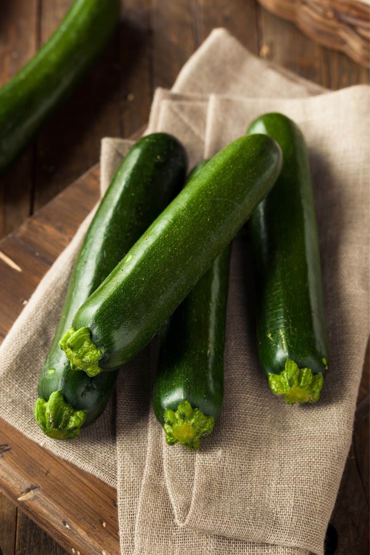 Whole zucchini squash on burlap napkin.