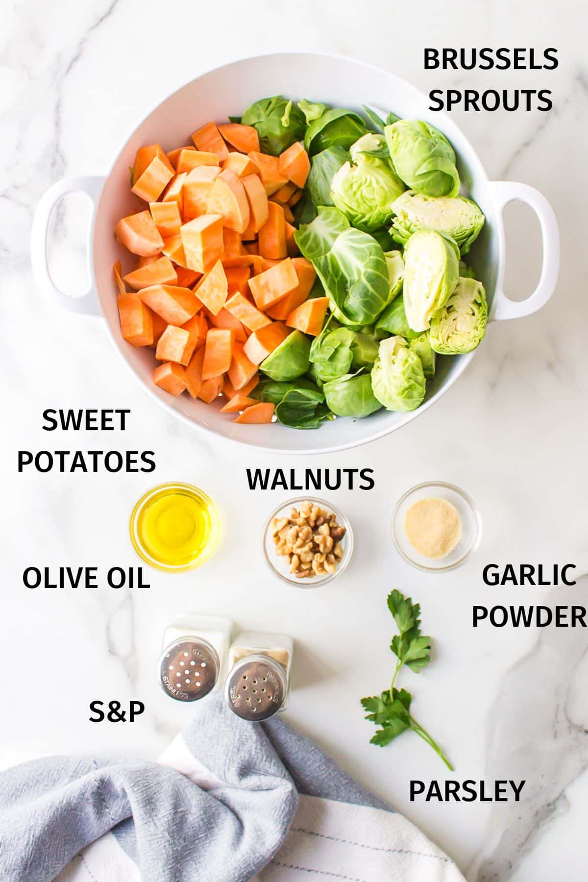 Ingredients to make roasted sweet potatoes and Brussels sprouts on a white background.