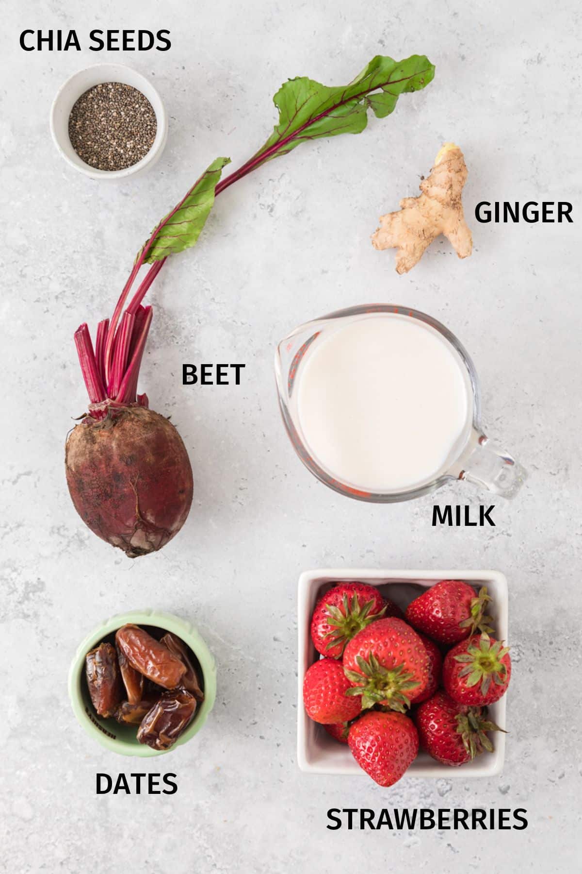 Ingredients to make a strawberry beet constipation smoothie on a white surface.
